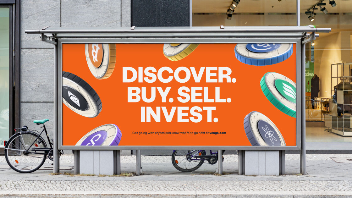 Venga billboard mock up. The billboard shows various crypto coins. Each coin type has a central circular colour - including orange, aqua, blue, purple and black - which is also repeated along its edge. The centre circle contains the coin's icon and shortened name in white. Each coin type has its own subtle textured brand pattern. The coins float in front of an orange background. The headline reads 'Discover. Buy. Sell. Invest' in white bold all caps. There is a small call to action line with a weblink to venga.com. The billboard is placed within a street scene, there is a concrete wall and shopfront behind it. Two bikes in partial view lean against it.