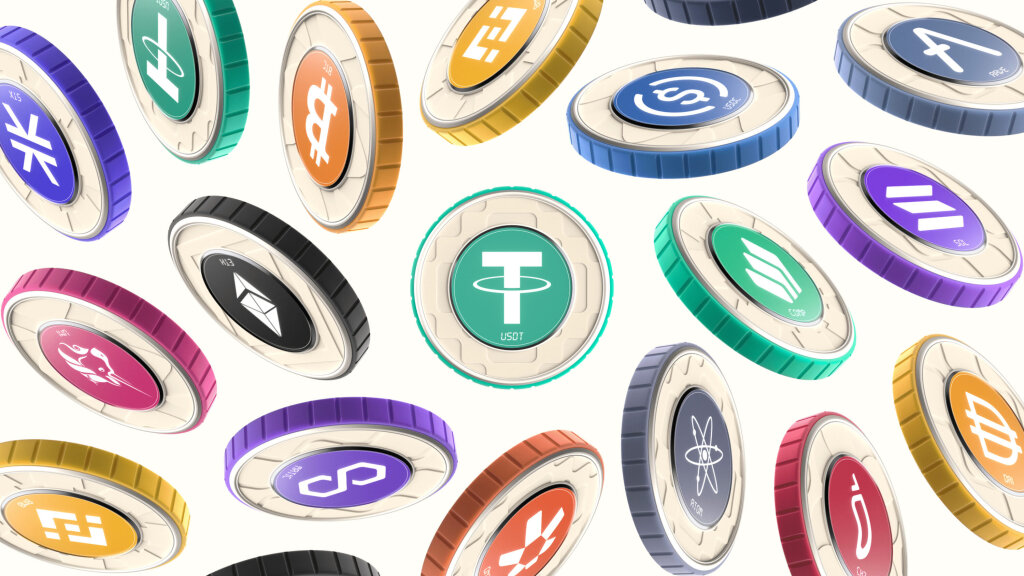 Venga crypto coins mock up. A range of coins is shown floating against a white background. Each coin type has a central circular colour - including orange, aqua, pink, blue, purple and black - which is also repeated along its edge. The centre circle contains the coin's icon and shortened name in white. Each coin type has its own subtle textured brand pattern.